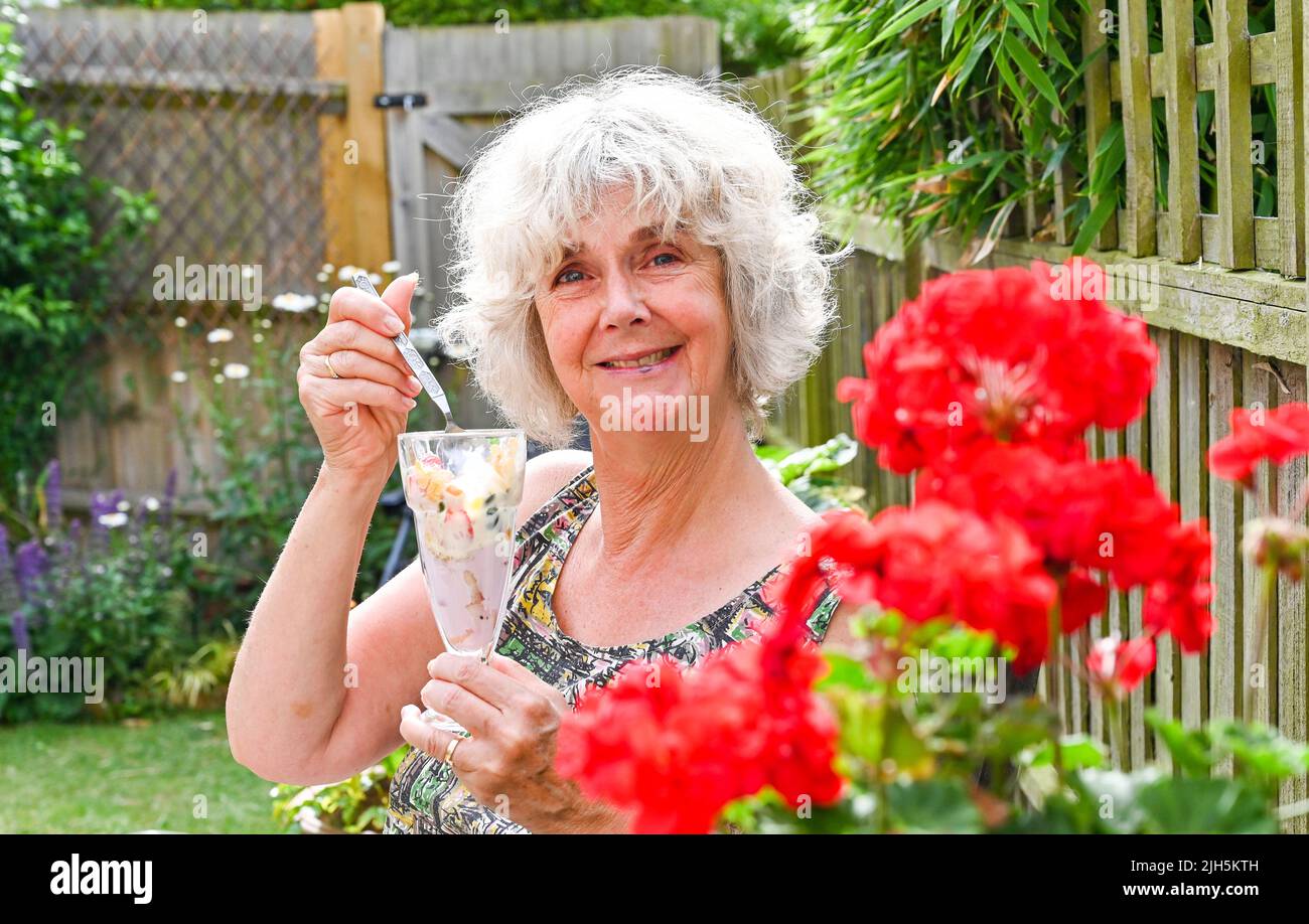 Woman eating outdoors in garden a healthy summer breakfast of yoghurt  , flakes , granola and fresh strawberries  UK Stock Photo