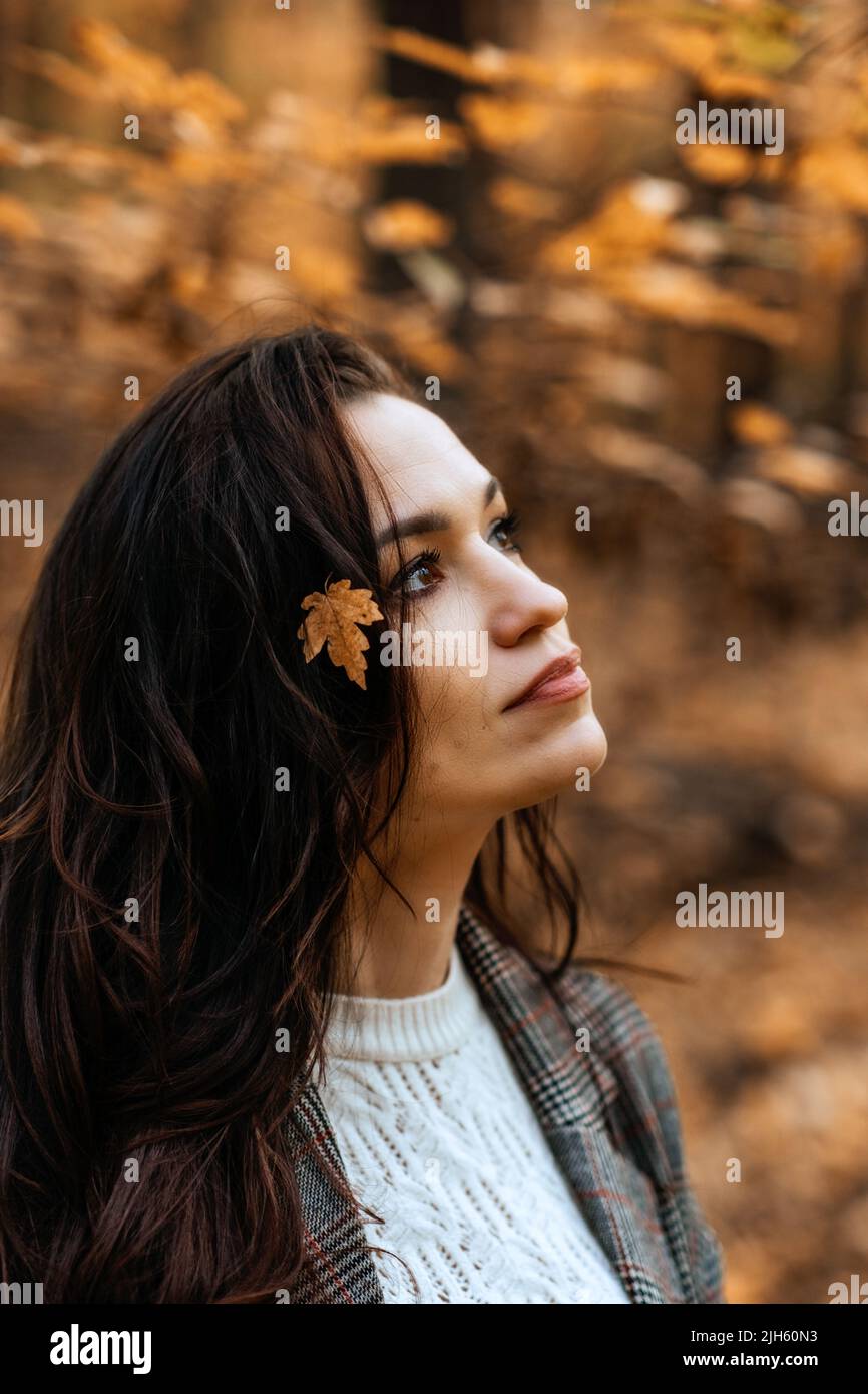 Portrait brunette woman with fall yellow leaves in long hair on autumn ...