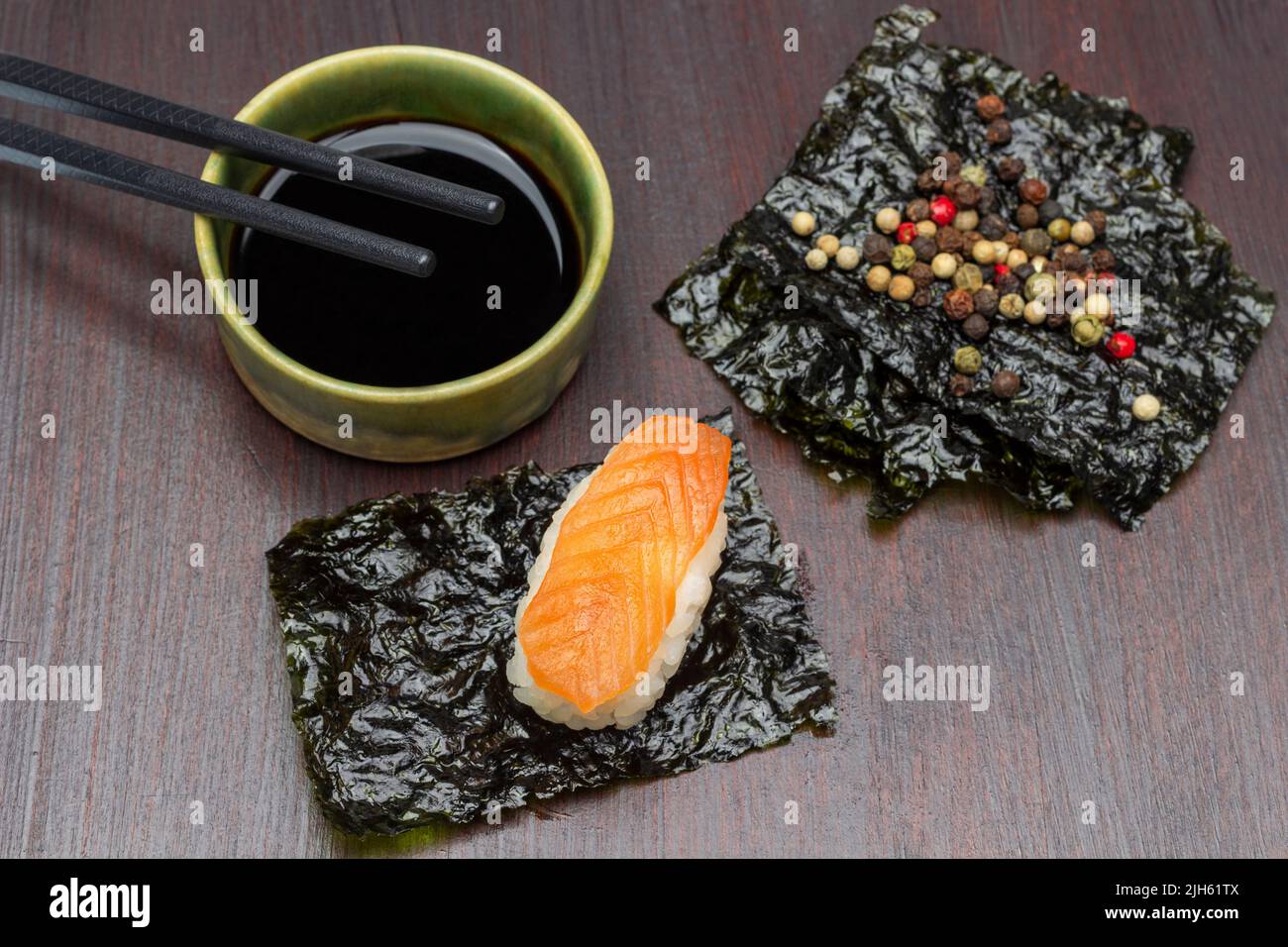 Sushi with salmon on nori sheet. Allspice on nori sheet. Soy sauce and