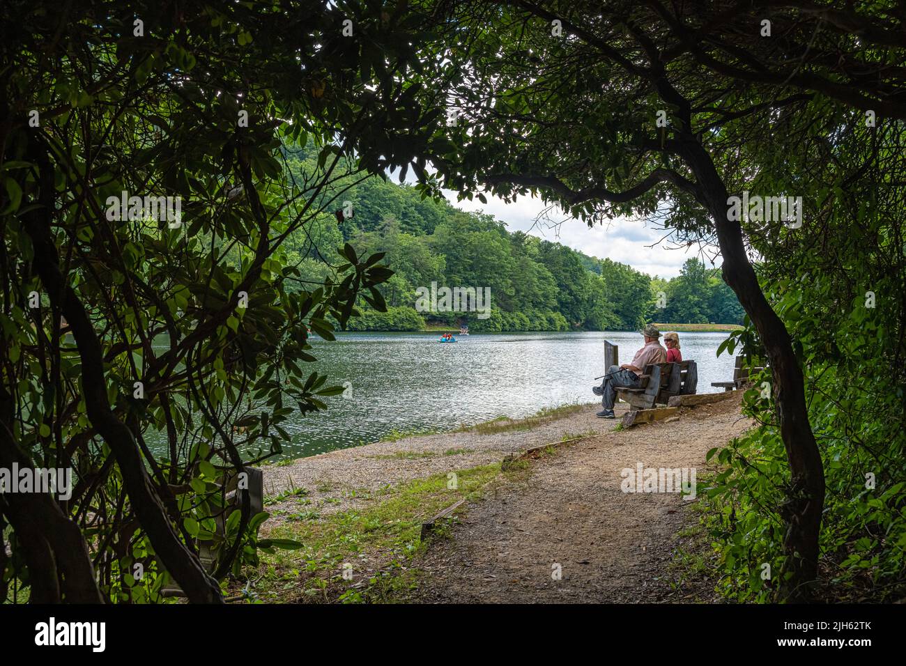 Senior couple enjoying the view from a lakeside bench along the Lake Trahlyta trail at Vogel State Park in the Northeast Georgia Mountains. (USA) Stock Photo