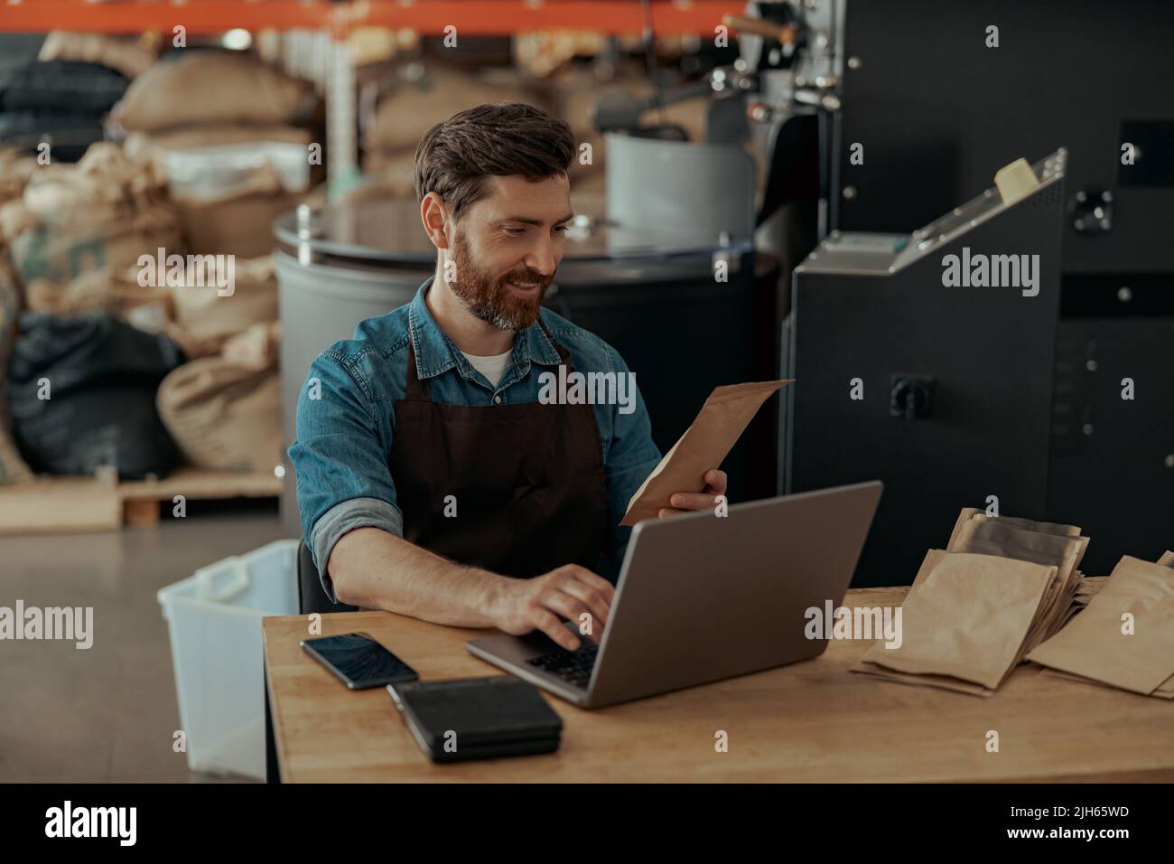 Business owner of small coffee roasting factory working laptop on his
