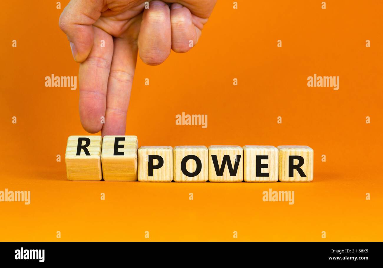 Power or repower symbol. Businessman turns wooden cubes and changes concept words Power to Repower. Beautiful orange table orange background. Business Stock Photo