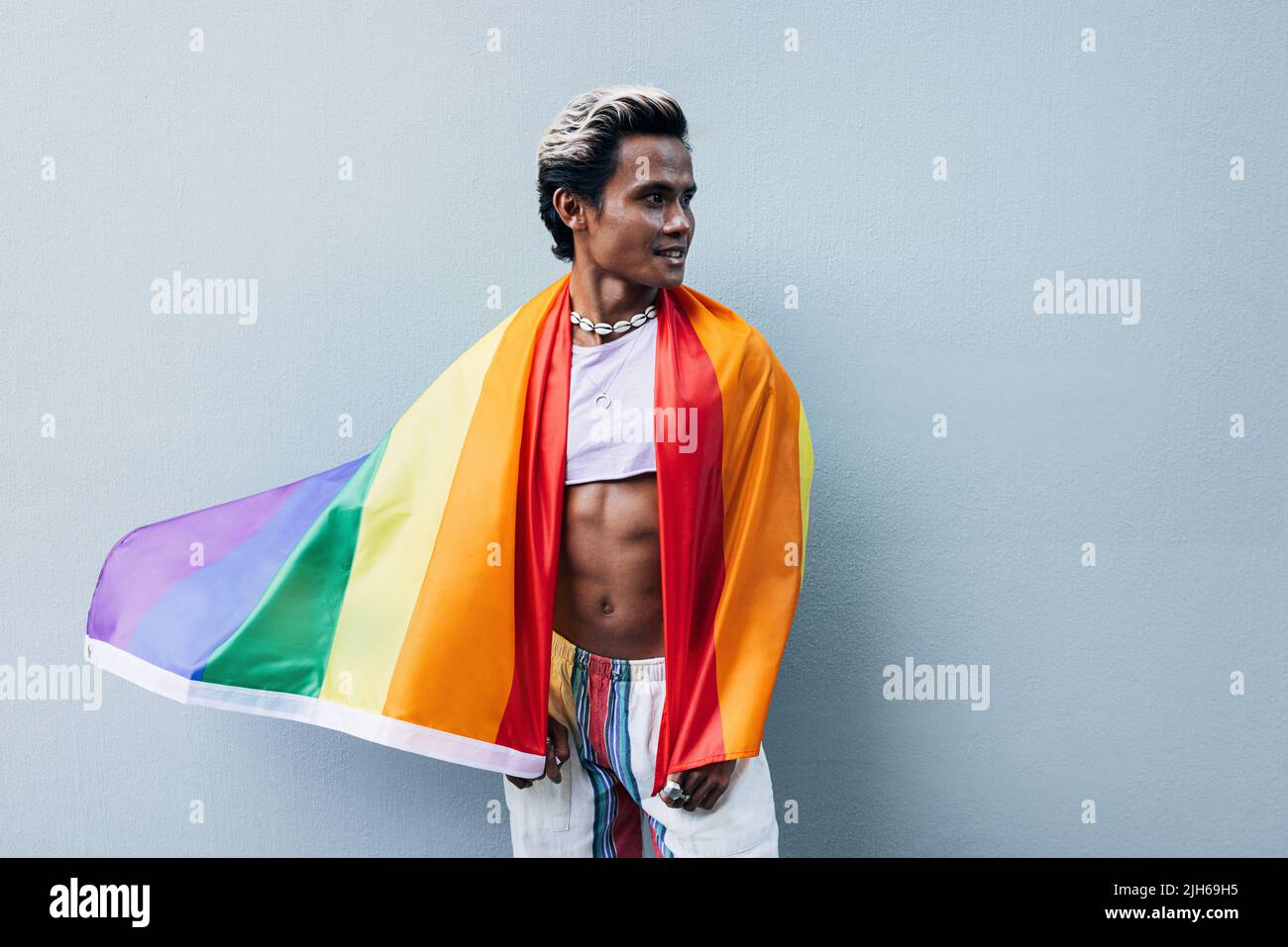 Handsome muscular man posing against grey wall with rainbow flag Stock ...