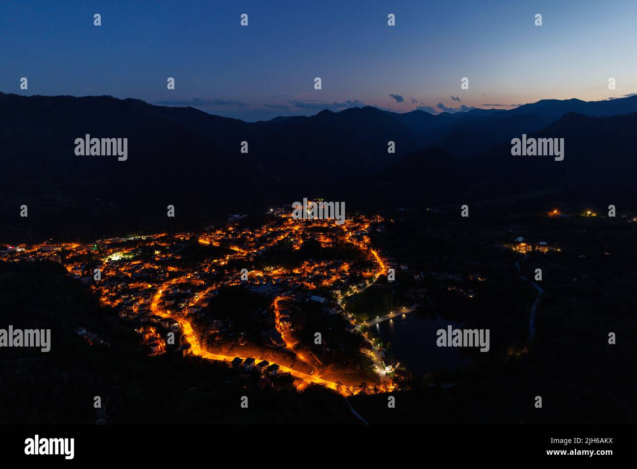 Bright sparkling mountain town of Smolyan with multi-colored night electric lights, against the backdrop of the mountain range of the Rhodope Mountain Stock Photo