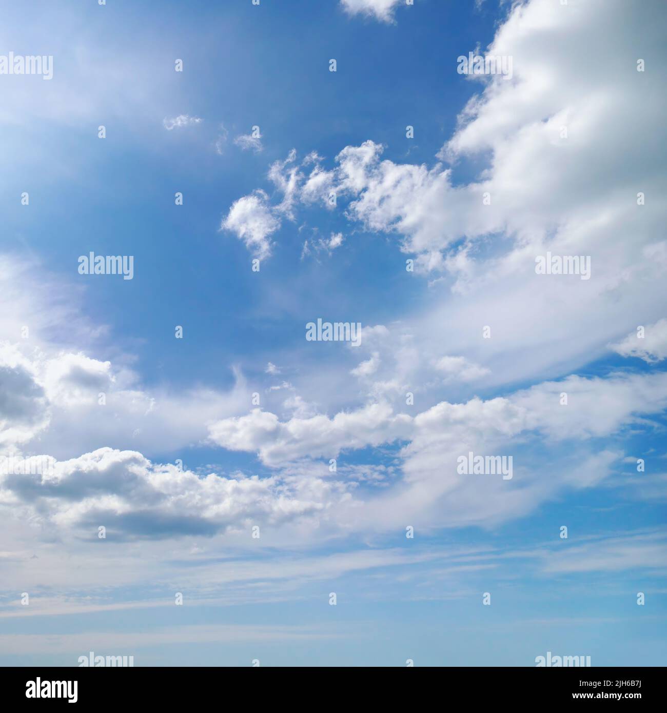 Bright summer sun on blue sky with white clouds. Stock Photo