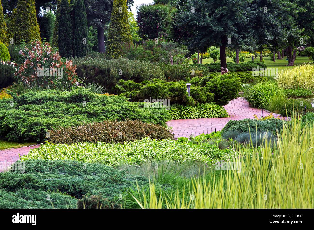 winding way pedestrian walkway of stone tiles in park with landscape