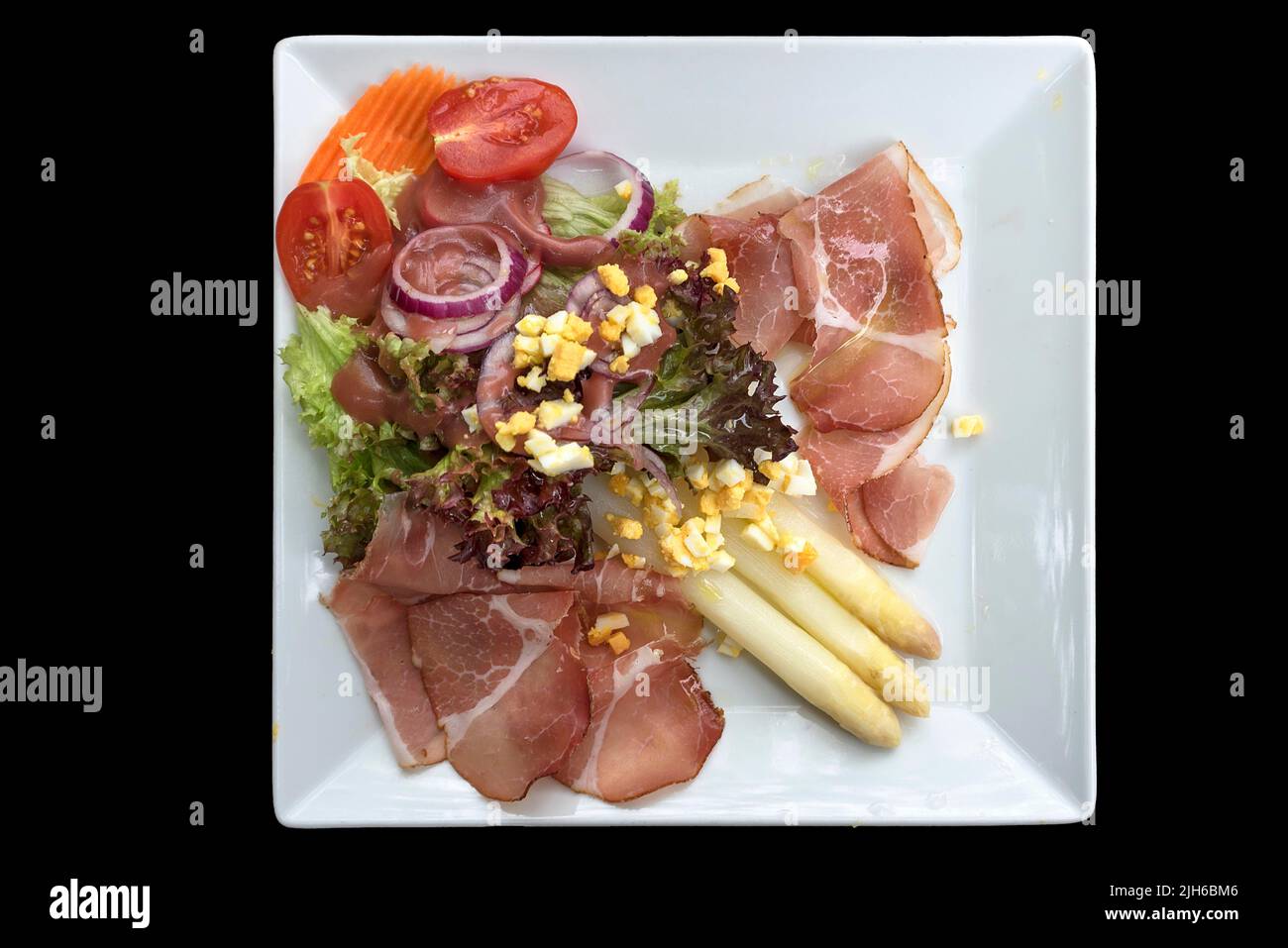 Asparagus salad with ham on a black background, Bavaria, Germany Stock Photo