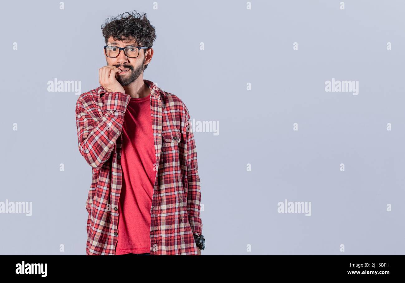 Nervous man with worried expression, bites his nails and looks anxiously. Person with worried expression biting his nails, concept of nervous man Stock Photo