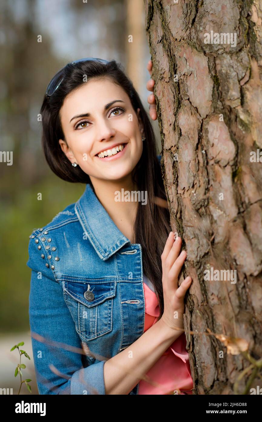 Woman leaning against tree trunk Stock Photo - Alamy