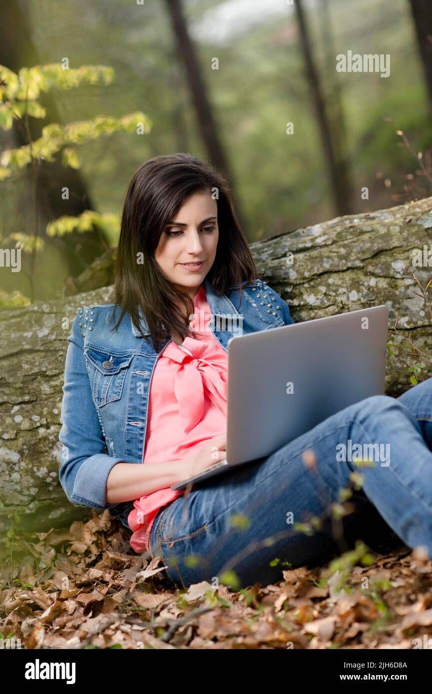 Young woman sitting in the forest with laptop Stock Photo - Alamy