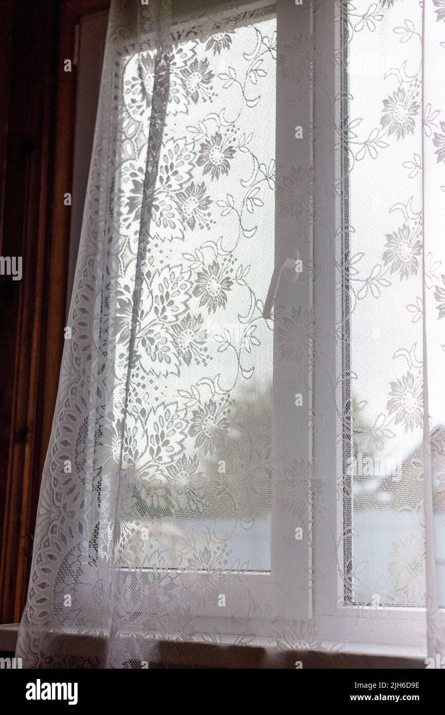 Window with openwork curtains. Transparent curtains with patterns. Stock Photo