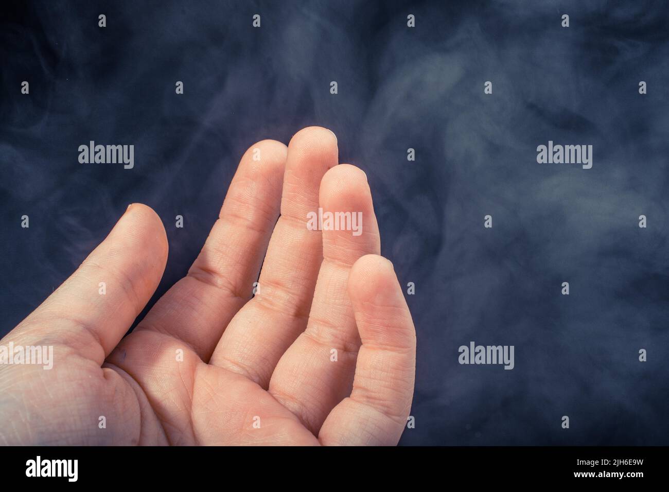Hand making a gesture on a black smoky background Stock Photo