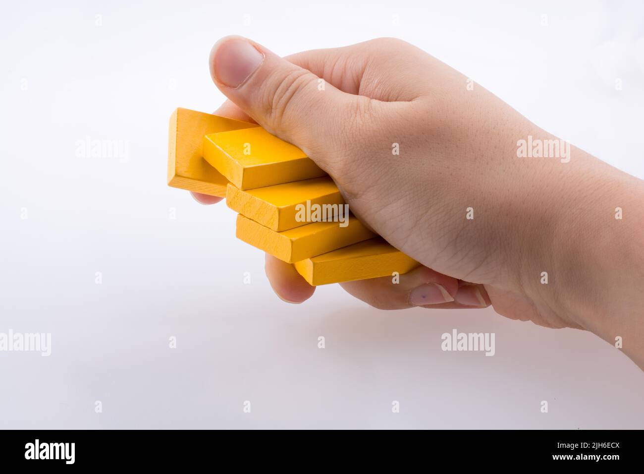 Hand holding yellow color domino pieces in hand Stock Photo