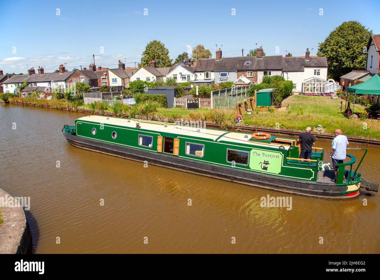 People on a canal narrowboat holiday passing canal side cottages approaching  lock 63 at Malkins Bank Cheshire on the Trent and Mersey  canal Stock Photo
