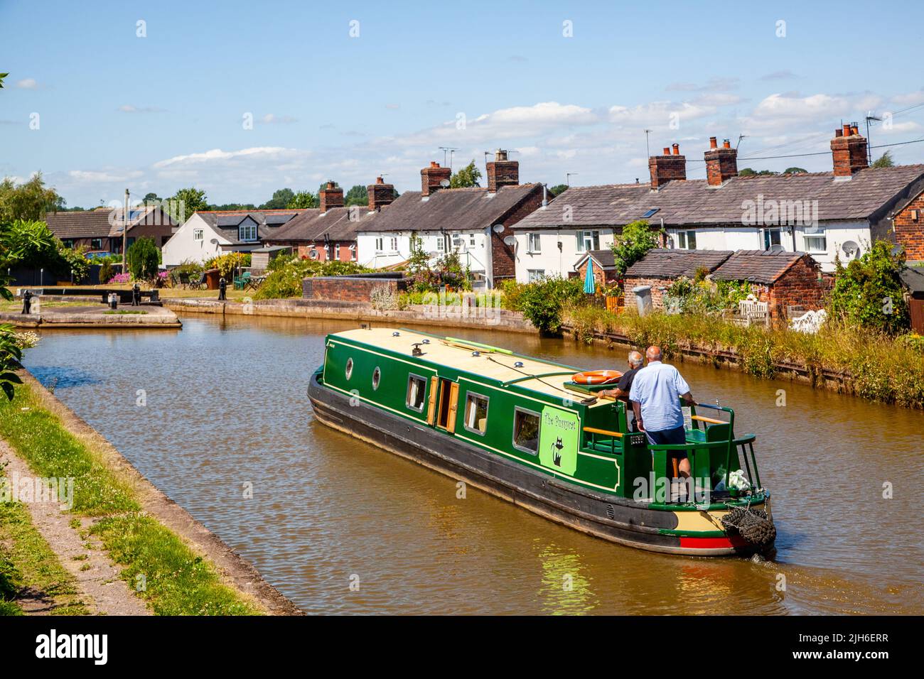 People on a canal narrowboat holiday passing canal side cottages approaching  lock 63 at Malkins Bank Cheshire on the Trent and Mersey  canal Stock Photo
