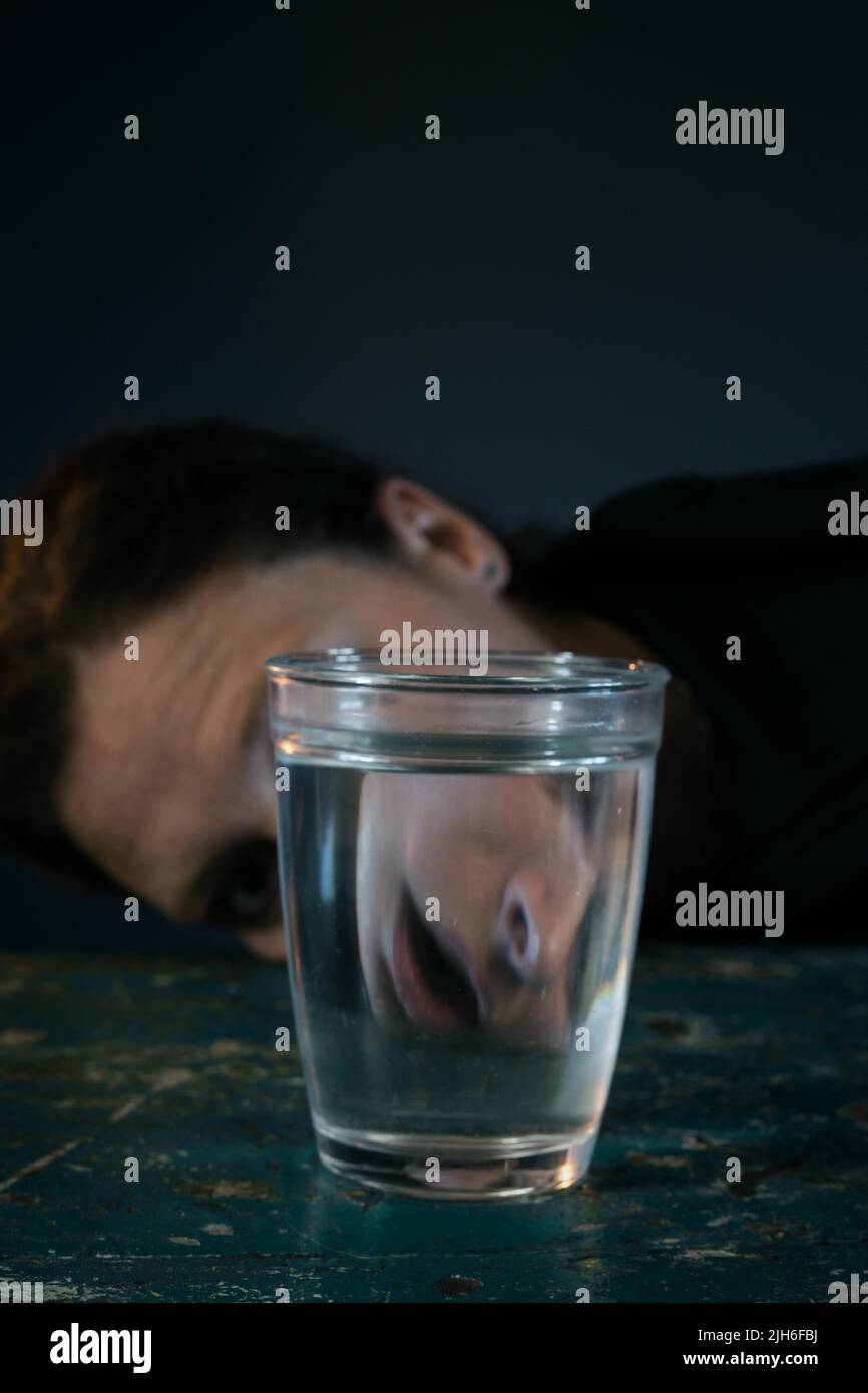 Creepy face of a woman reflected in a glass of water Stock Photo
