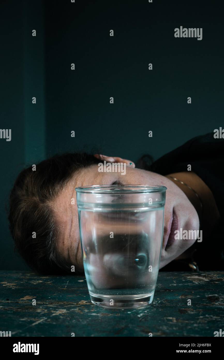 Creepy face of a woman reflected in a glass of water Stock Photo
