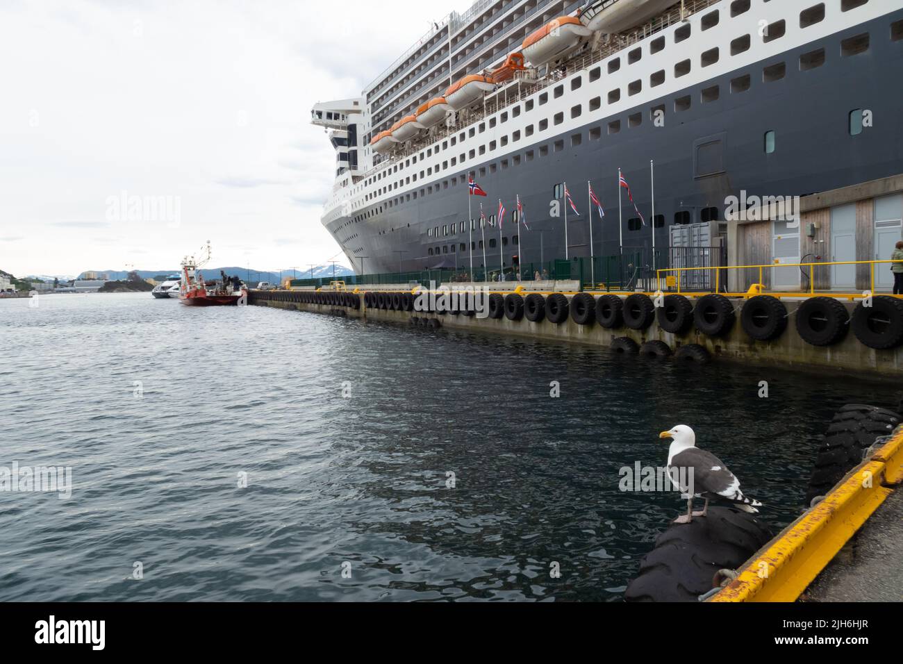 The Cunard Line Queen Mary 2 cruise ship is docked in the port of Alesund, Norway. Stock Photo