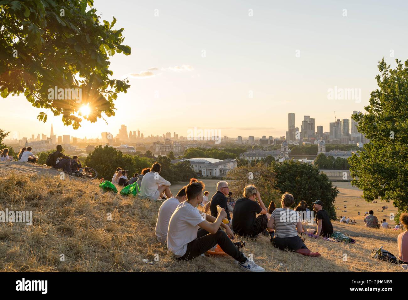 London UK, 15th July 2022.  UK Weather.  General public flock to Greenwich park sitting on ground to enjoy the hot summer sunset on Friday afternoon as sun rays  dries up the grass  in the park, An UK national emergency has been declared after a red extreme heat warning was issued for the first time, as temperatures could hit 40C next monday, London England. Credit: Xiu Bao/Alamy Live News Stock Photo