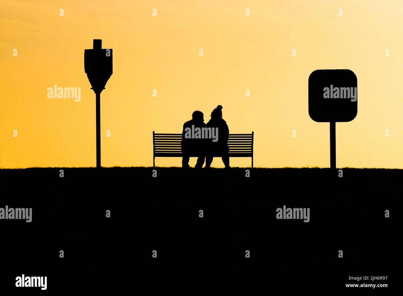 Couple sitting on a bench in love silhouette Stock Photo