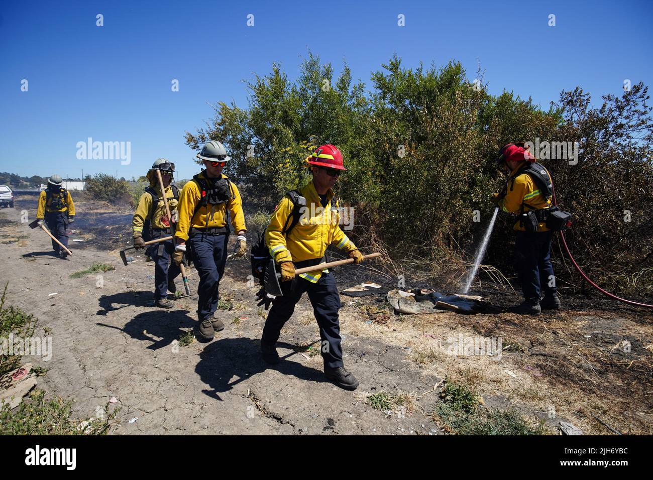 Firefighters walk back to the fire truck after the brush fire is ...