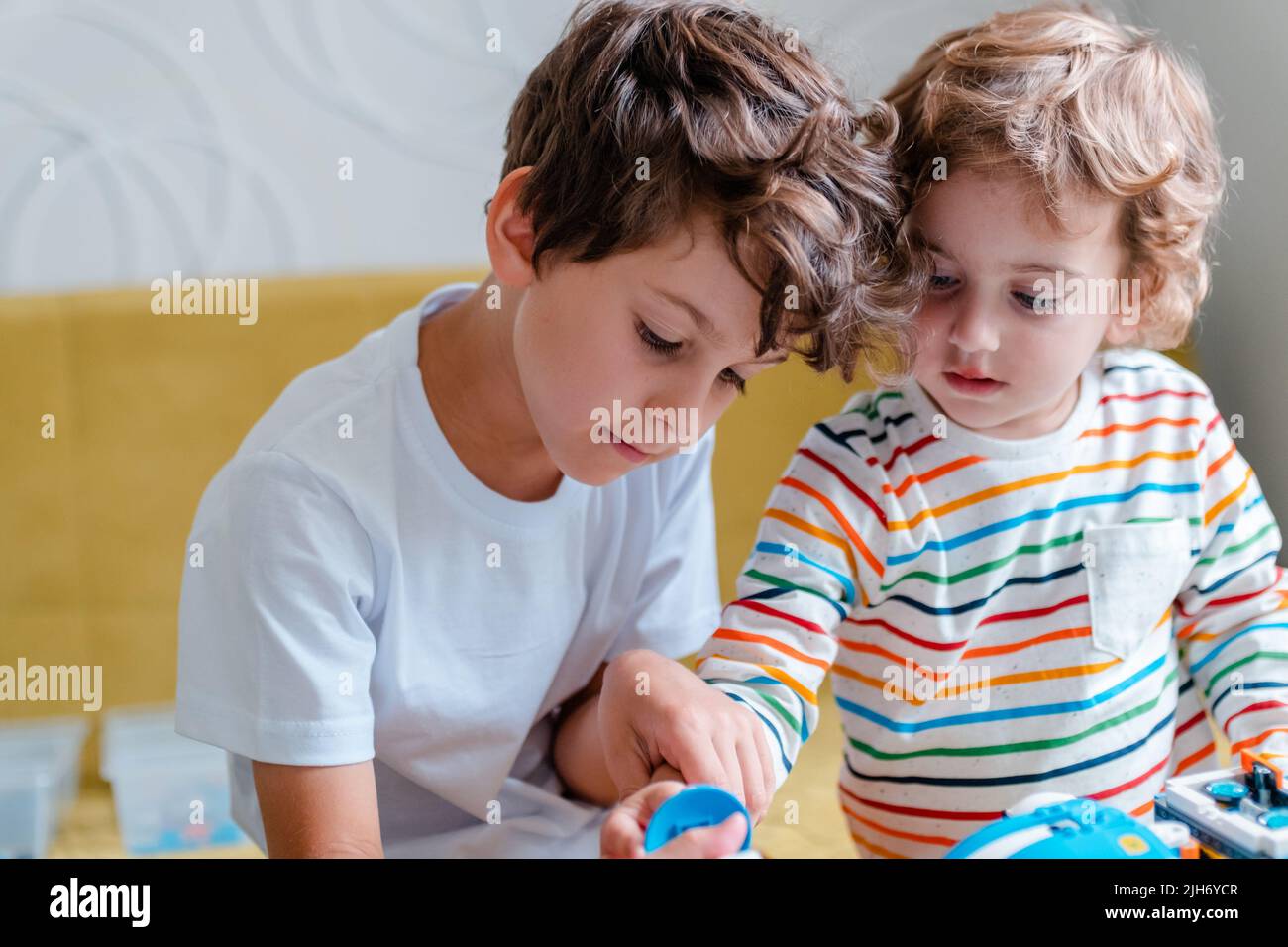 Kid collects robot from plastics details and programmed on tablet, robotics. Stock Photo