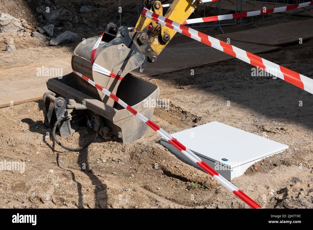 Backhoe loader of excavator wrapped with red striped tape. the concept of the end of the working day at the construction site and safety Stock Photo