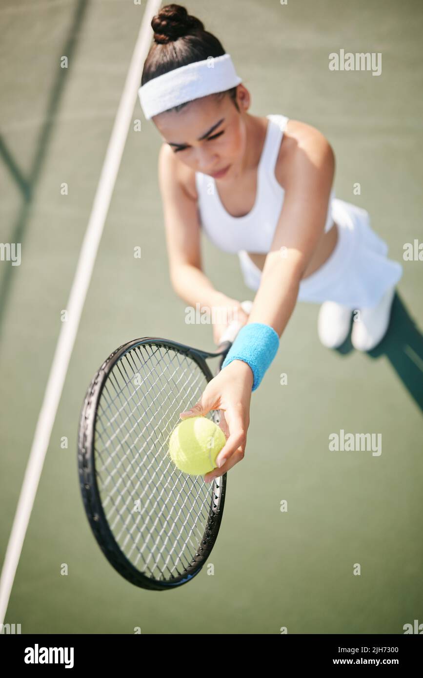 My opponents not going to know what hit them. High angle shot of a young tennis player standing on the court and getting ready to serve during Stock Photo