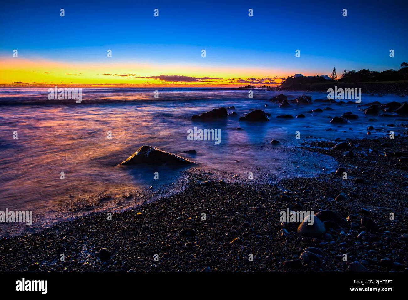 Dark pre-dawn scenic seascape in Forster town on Pacific coast of Australia - Pebbly beach with pebbles. Stock Photo