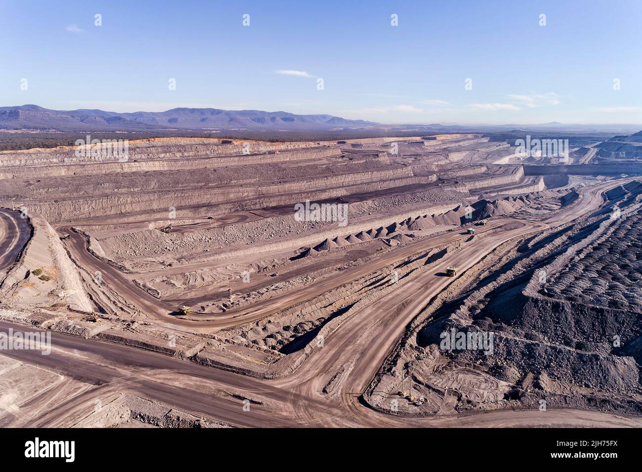 Pale sky over open pit black coal mine in Hunter valley of Australia - aerial industrial landscape. Stock Photo