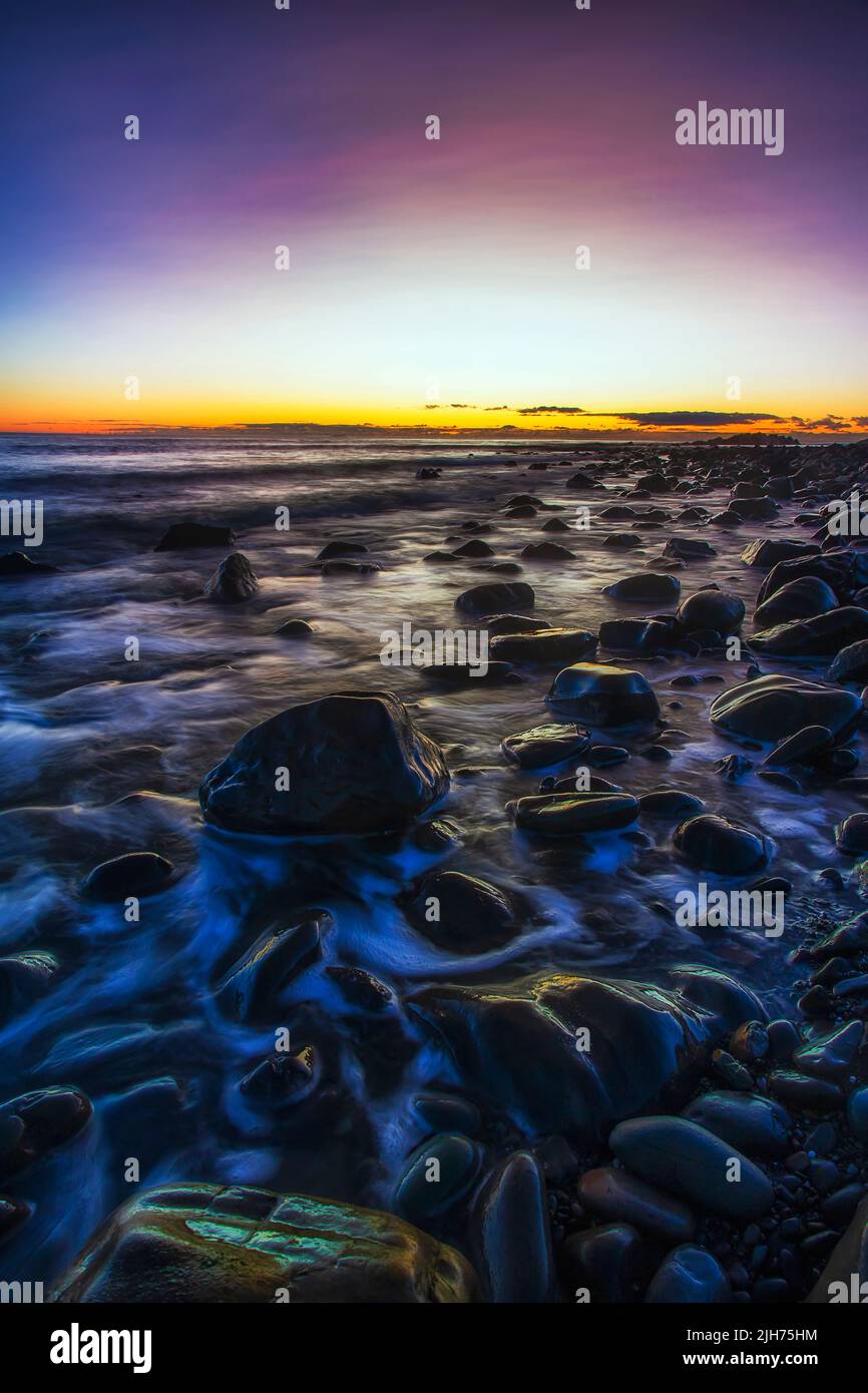 Pebbles on Pebbly beach of Forster town in Australia on Pacific coast - scenic seascape sunrise. Stock Photo