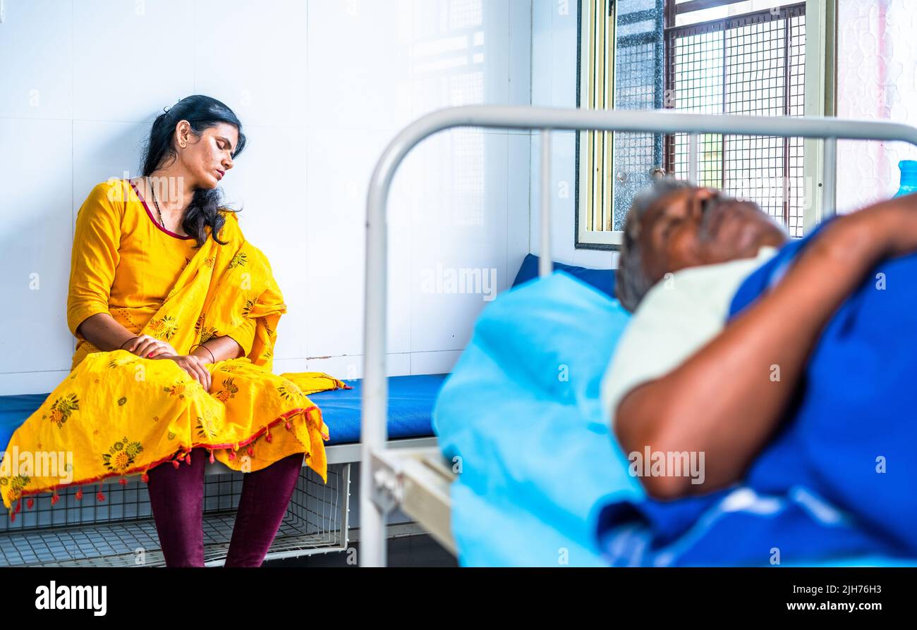 tired or exhausted Daughter sleeping behind the sick elderly father at hospital ward - concept of caring, medical treatment and relationship bonding Stock Photo