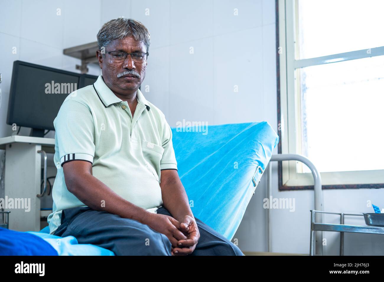 worried thoughtful sick elderly man sitting on bed of hospital - concept of depression, mental health problems and medical treatment Stock Photo
