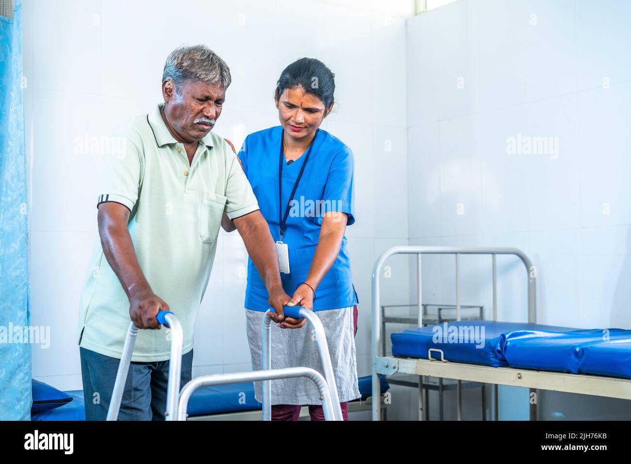 nurse helping recovered senior injured patient to walk using walker at hospital ward - concept of professional occupation, medicare and caretaker Stock Photo
