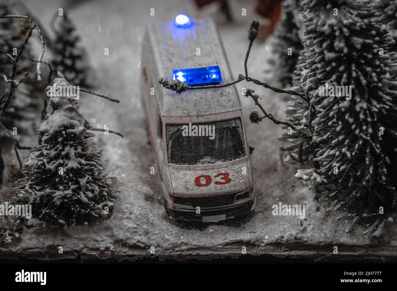 Toy representation of an ambulance vehicle stuck in snow amid the forest. Stock Photo