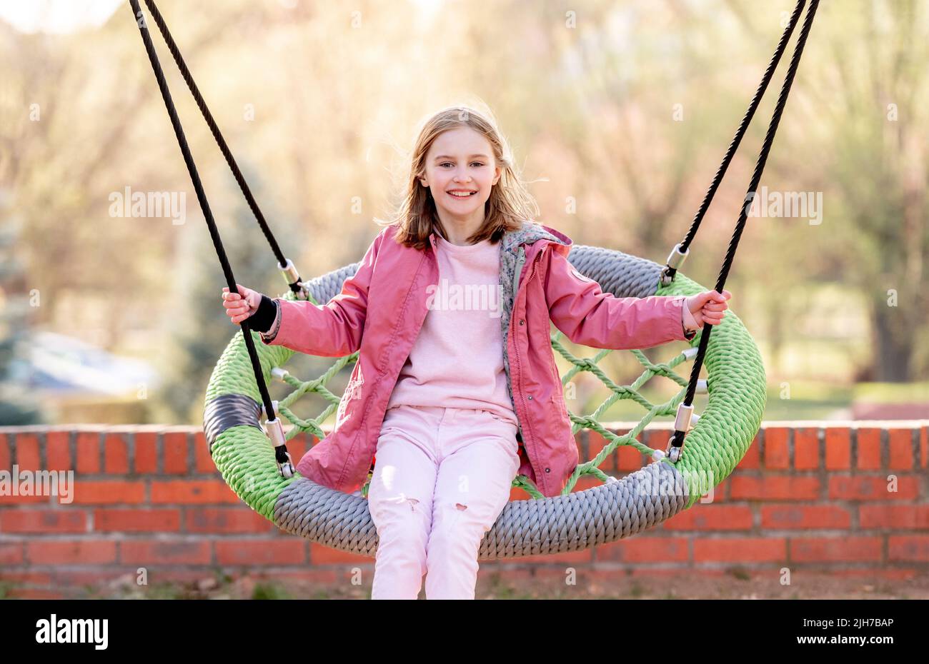 Beautiful little girl swinging on a round swing Stock Photo - Alamy