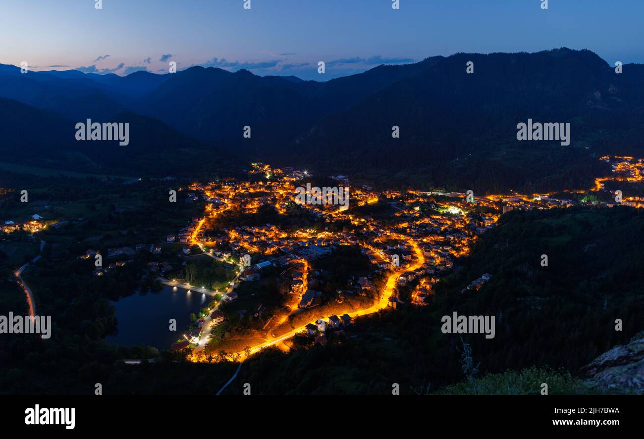 Bright sparkling mountain town of Smolyan with multi-colored night electric lights, against the backdrop of the mountain range of the Rhodope Mountain Stock Photo