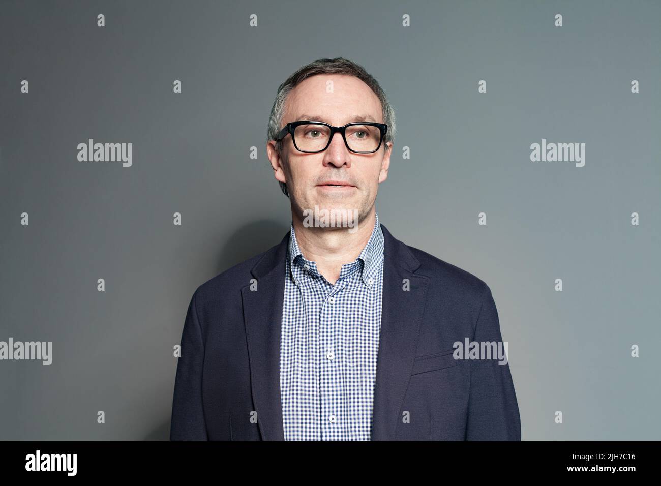 Portrait of 60 year old man in glasses on grey background Stock Photo Alamy