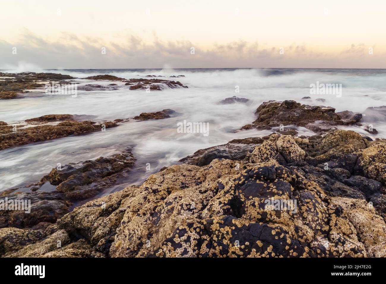 Landscape of the sea coast with water between the rocks, waves crashing against the rocks and reflections of the sky. Gran Canaria. Spain Stock Photo