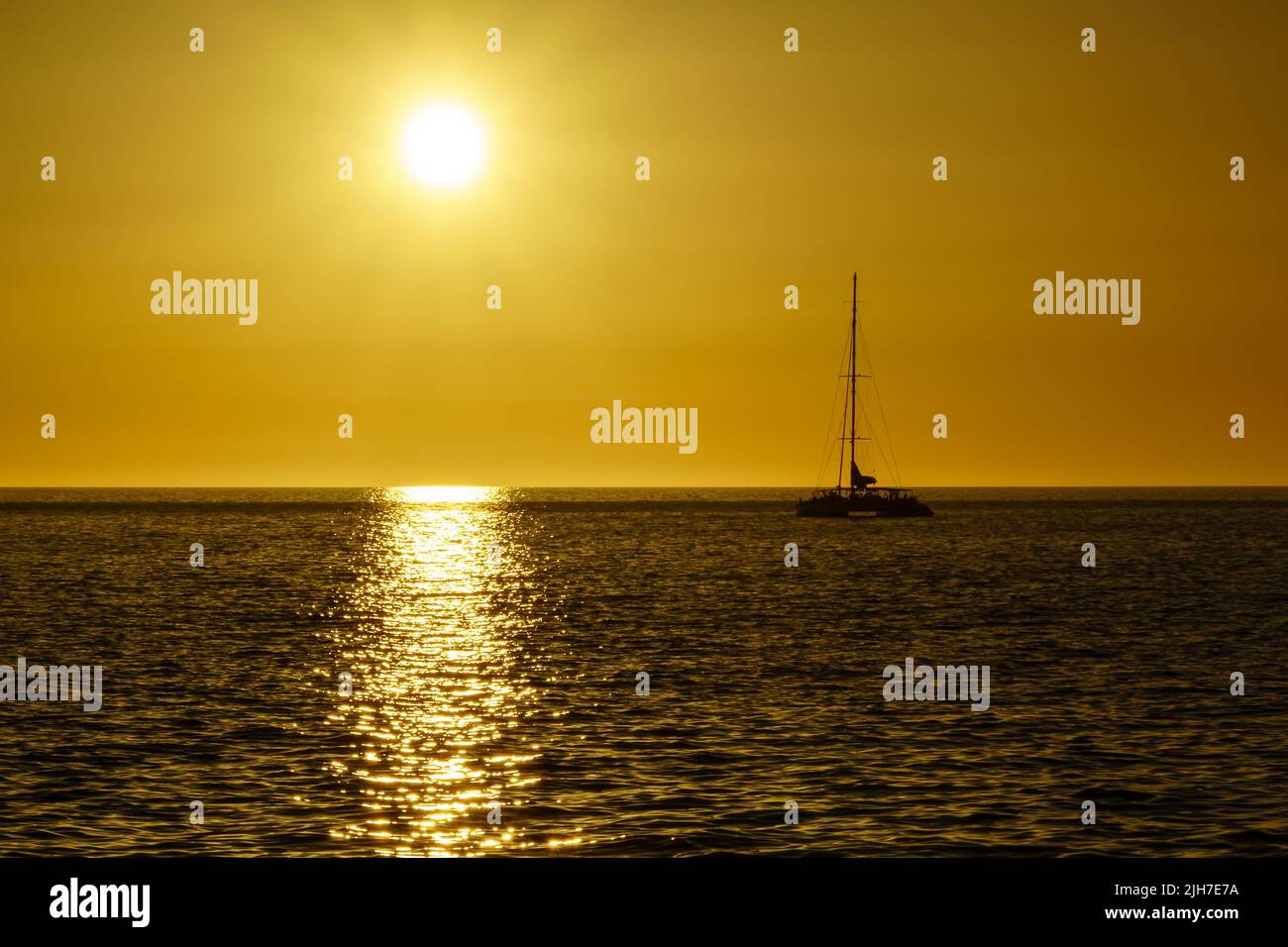 sunset in the sea with the sun on the horizon reflecting the light in the water and on the rocks on the shore. Gran Canaria. Spain Stock Photo