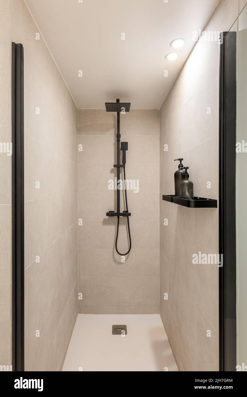 Modern shower zone with black rain head and hand held shower. Beige