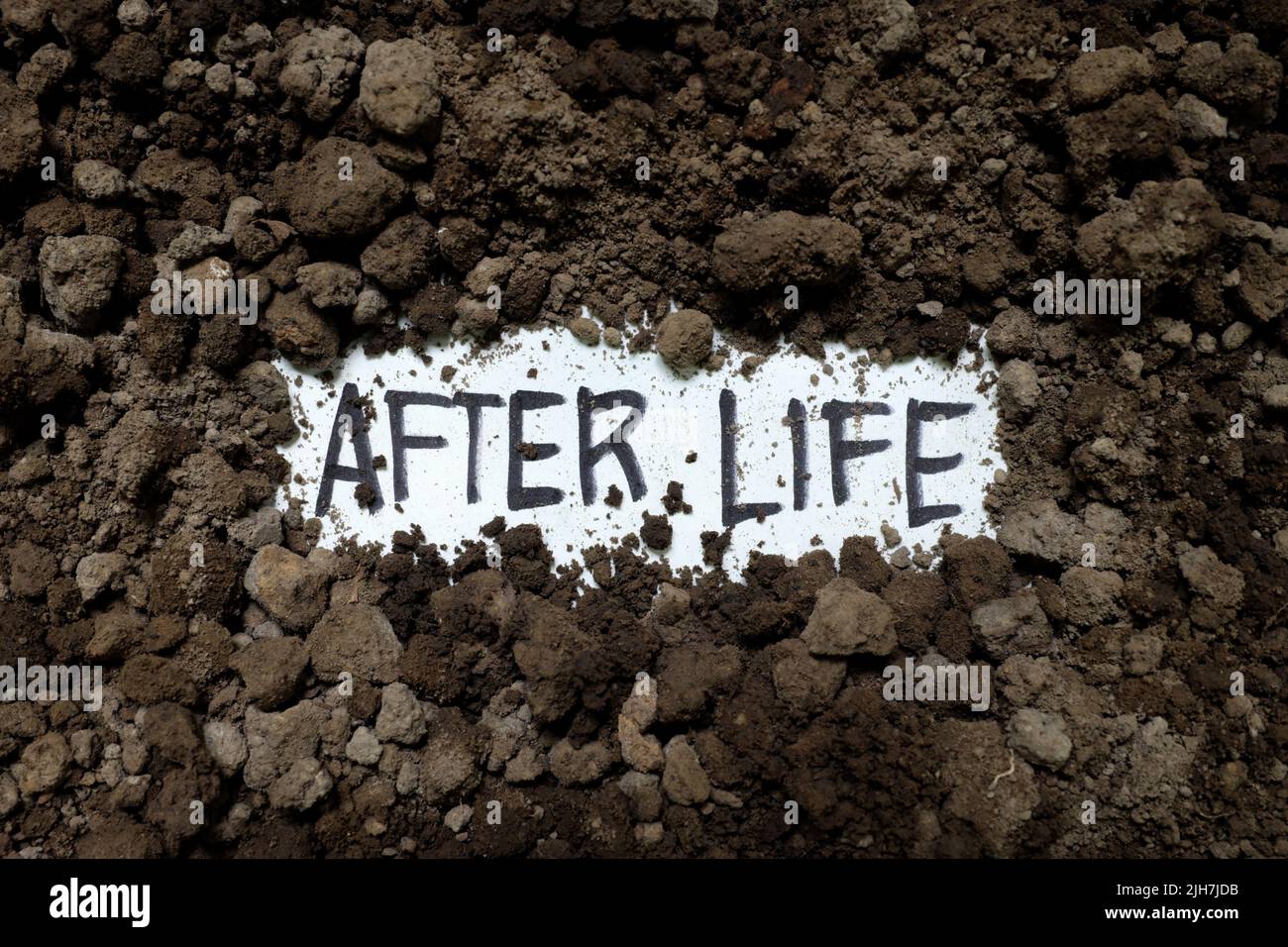 Afterlife concept. Written word on paper on dark black soil. Stock Photo