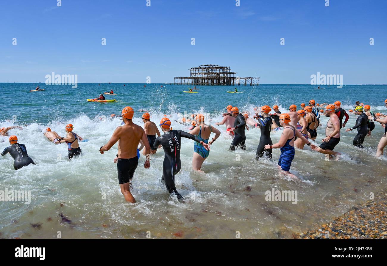 Brighton UK 16th July 2022 - Swimmers charge into the sea for the start of the Brighton Pier to Pier race on a hot sunny day . A red extreme weather warning has been issued for the beginning of next week as temperatures are expected to reach 40 degrees in some parts of Britain .  : Credit Simon Dack / Alamy Live News Stock Photo