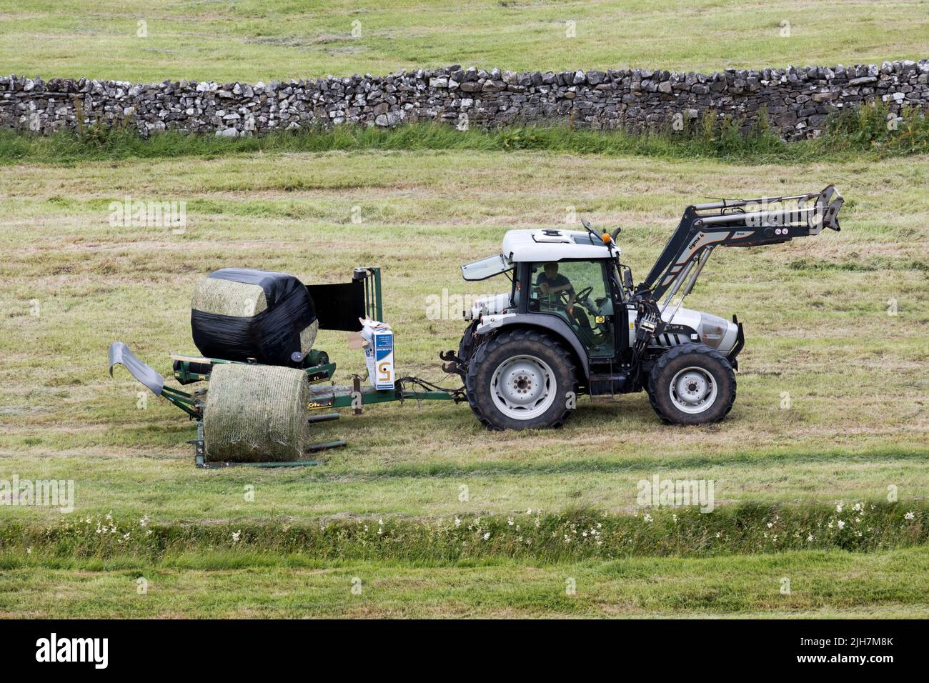 Summer haymaking, Hawes, Wensleydale, North Yorkshire. Round bales are wrapped with plastic to exclude air to make silage or haylage for winter feed. Stock Photo