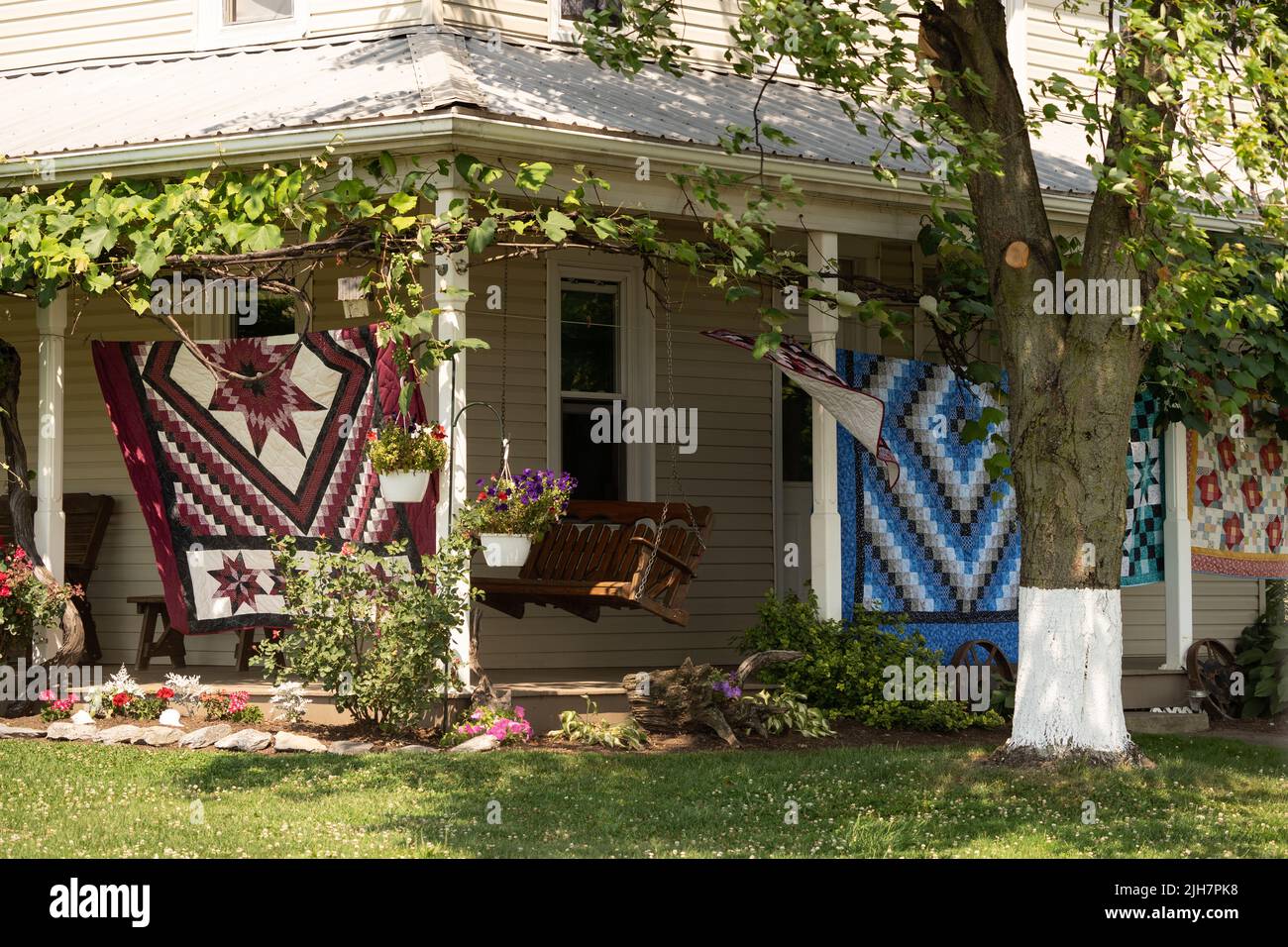 Ephrata, Pennsylvania: July 1, 2022: Beautiful handmade quilts displayed on front porch for sale on Amish Farm. Stock Photo