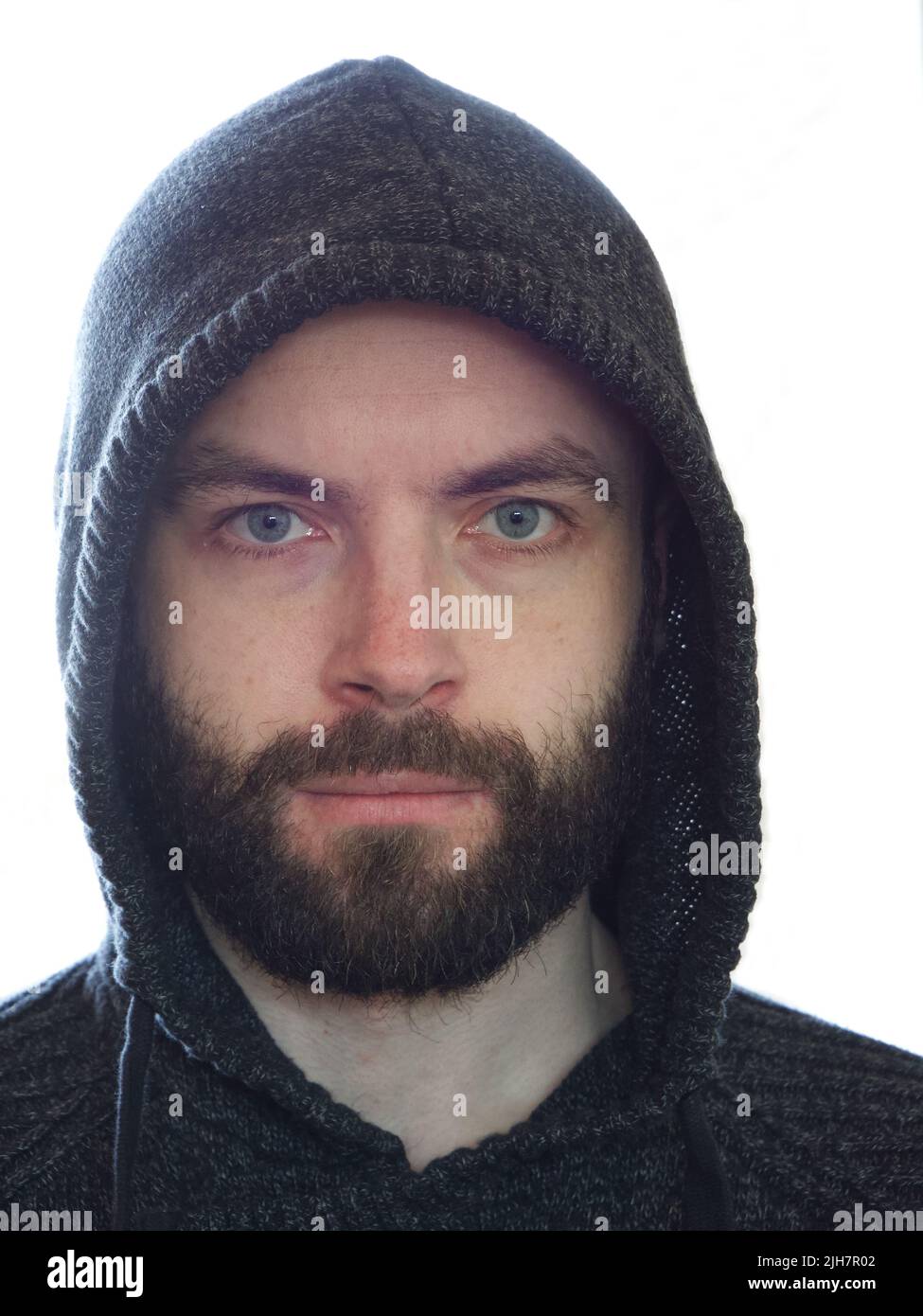 A bearded man in a hood, a close-up portrait. An untidy man. A close look. Stock Photo