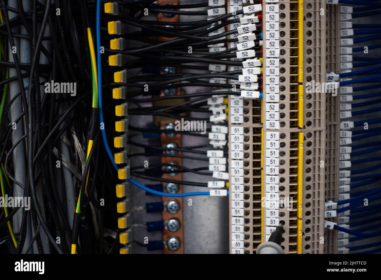 Electrical wiring harnesses connected to terminals in the control cabinet of an industrial machine. Cable ends marked with descriptions Stock Photo