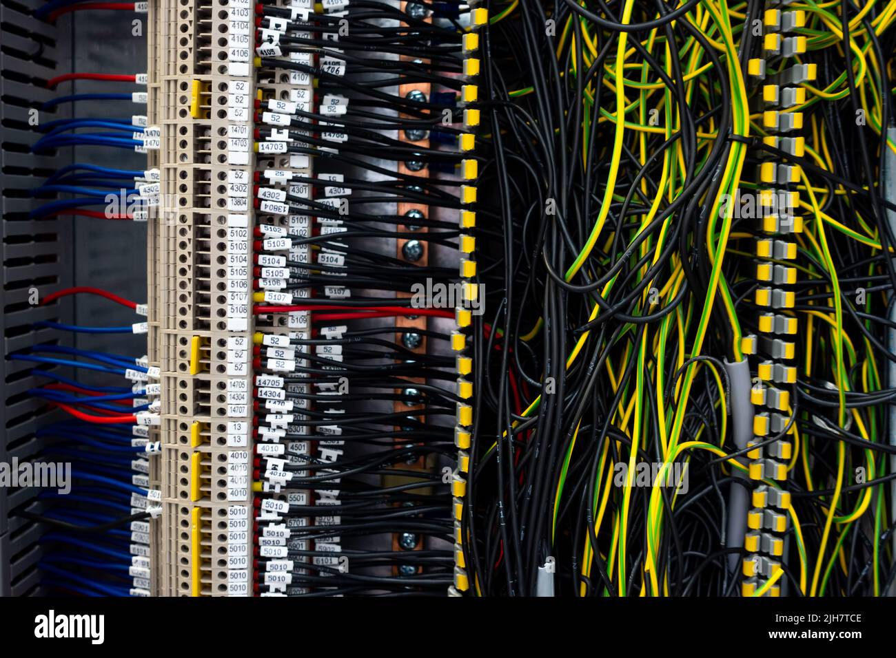 Electrical wiring harnesses connected to terminals in the control cabinet of an industrial machine. Cable ends marked with descriptions Stock Photo