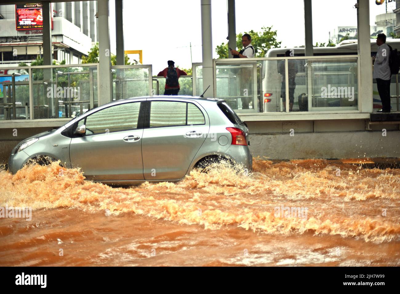 A car negotiating with floodwater on Thamrin Street in Central Jakarta, after a continuous rain left the capital city of Indonesia flooded. Stock Photo