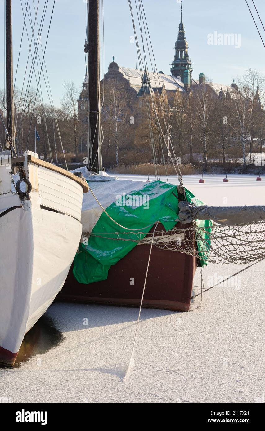 Boats trapped by ice in Djurgardsbrunnsviken bay with Djurgarden island and the Nordiska Museet (Nordic Museum) in background, Stockholm, Sweden Stock Photo